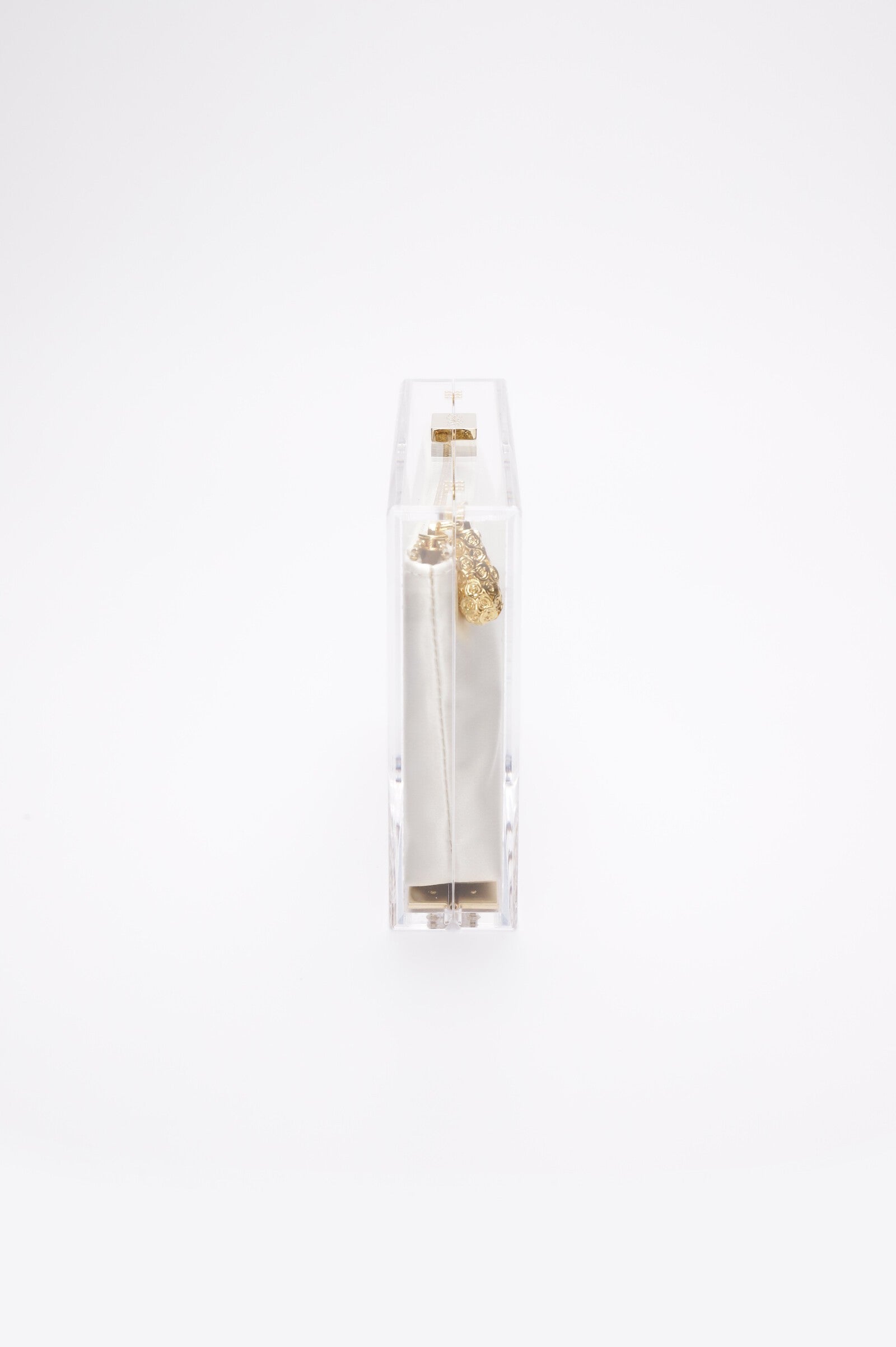 Side view of The Bella Rosa Collection's Mia Clutch, a clear acrylic design with an embroidered bridal crest ivory satin zipper pouch and gold-toned hardware. Perfect for special occasions, it exudes elegance and a hint of glamour.