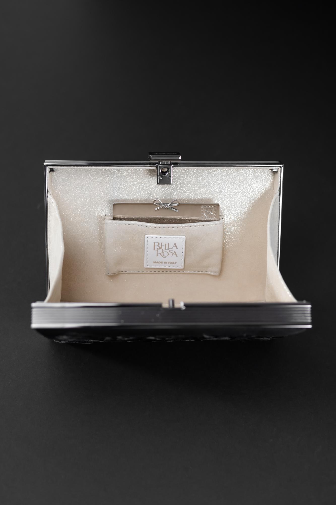 Open the silver-framed Europa Satchel with a beige lining, revealing a small inner pocket containing a cream-colored fabric tag with text.
