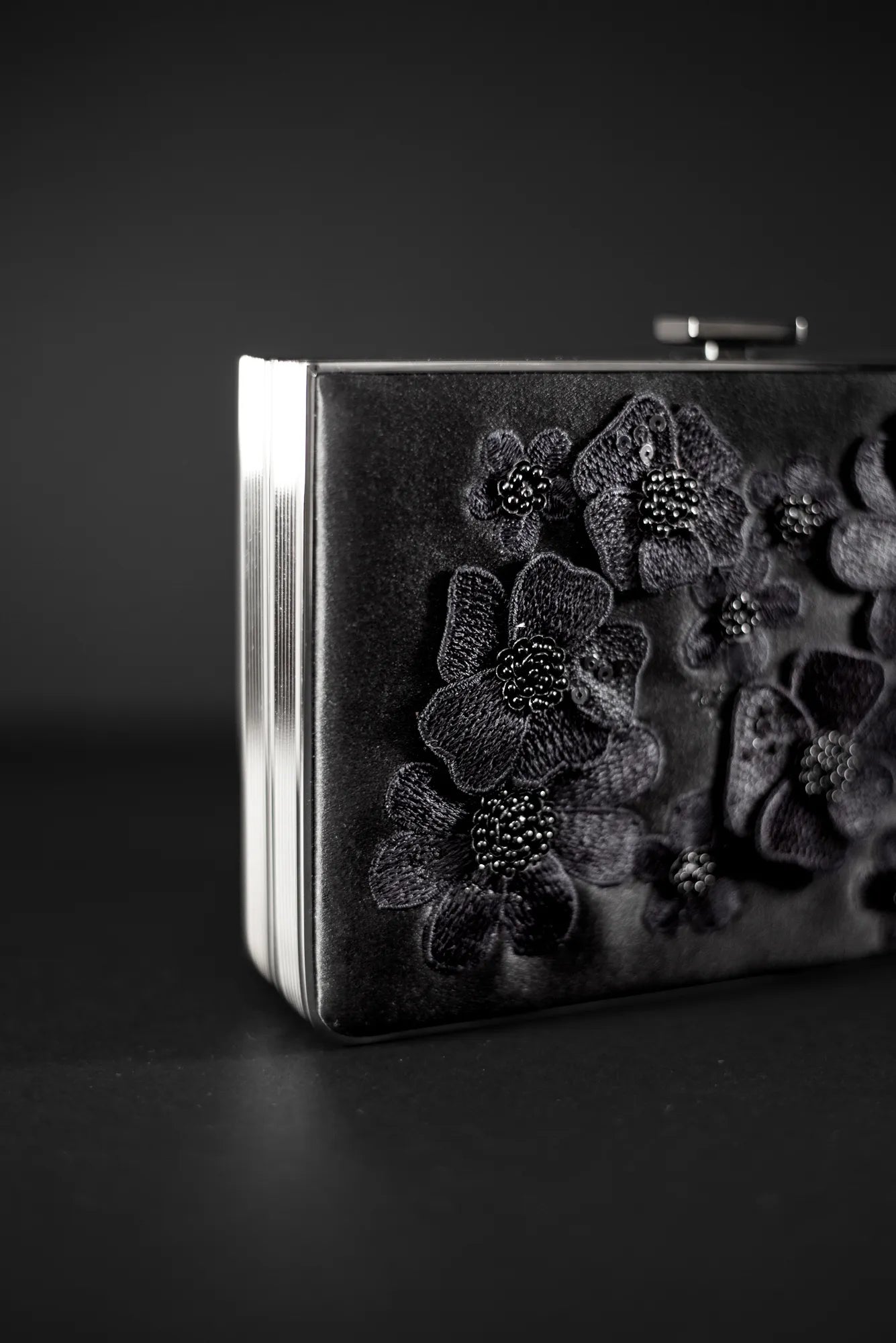 The Venezia Clutch x MICAELA Black Satin Floral Embroidery from The Bella Rosa Collection is a sample sale item, featuring intricate 3D floral embroidery against a dark background.