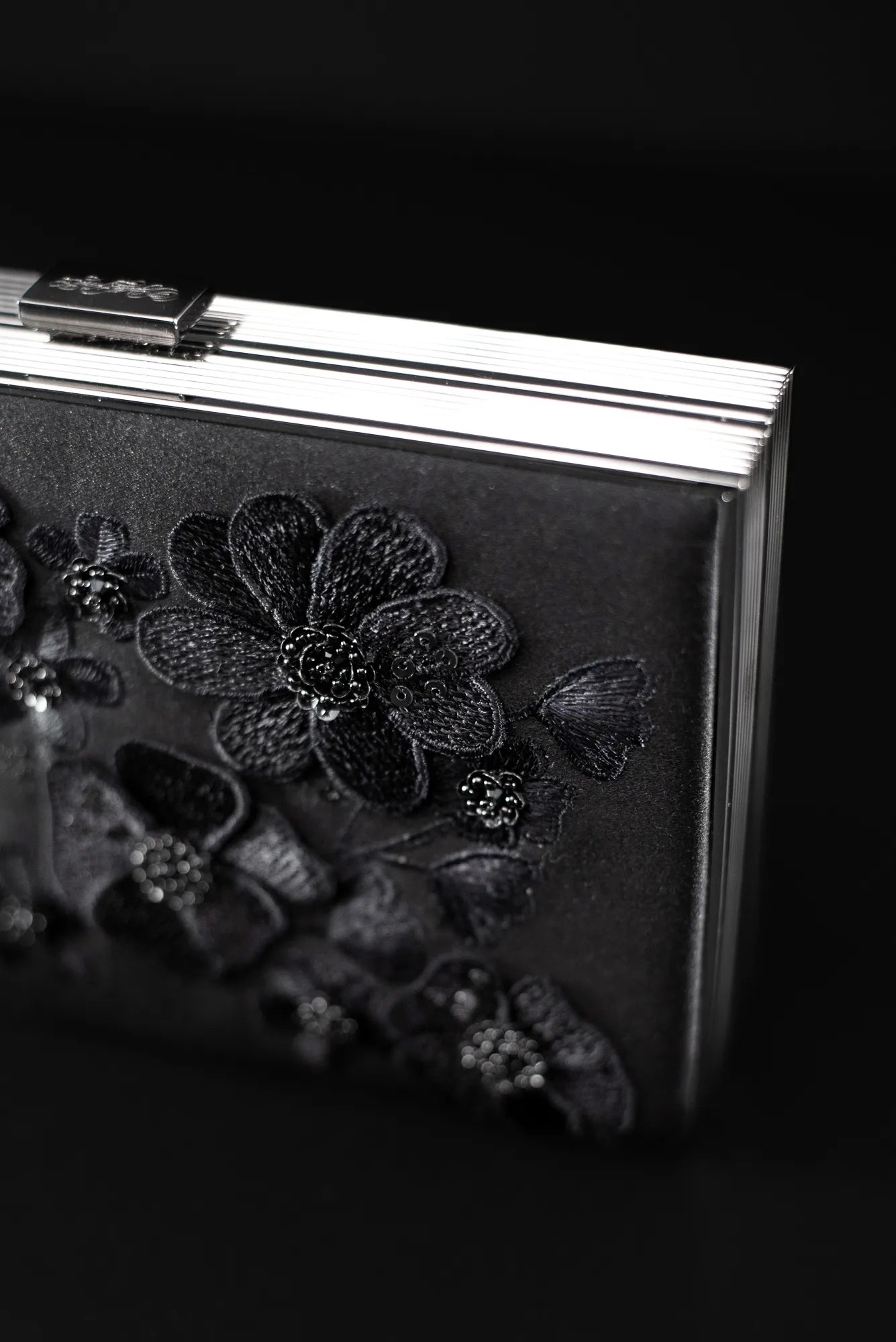 A Venezia Clutch x MICAELA from The Bella Rosa Collection, featuring black satin adorned with intricate 3D floral embroidery on the front. Sample Sale Item.