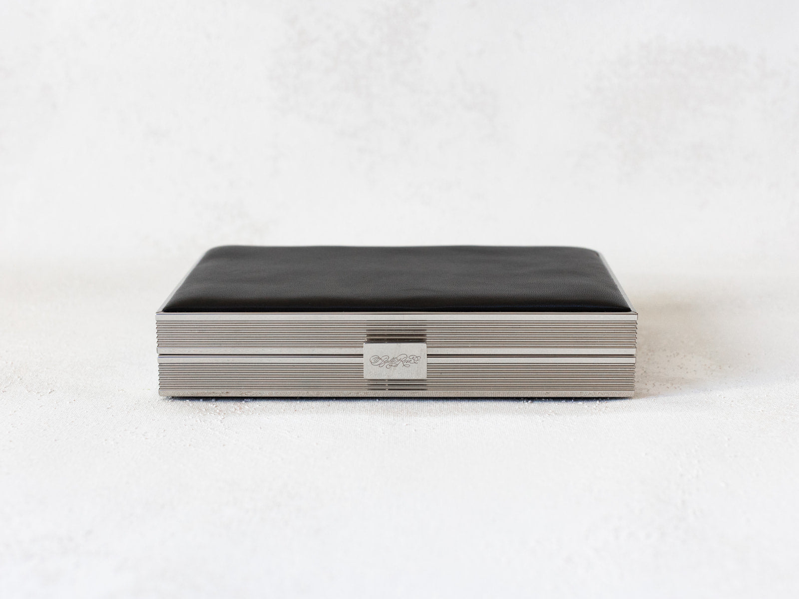 Top side view of Venezia clutch with silver rectangle frame and a black leather side.