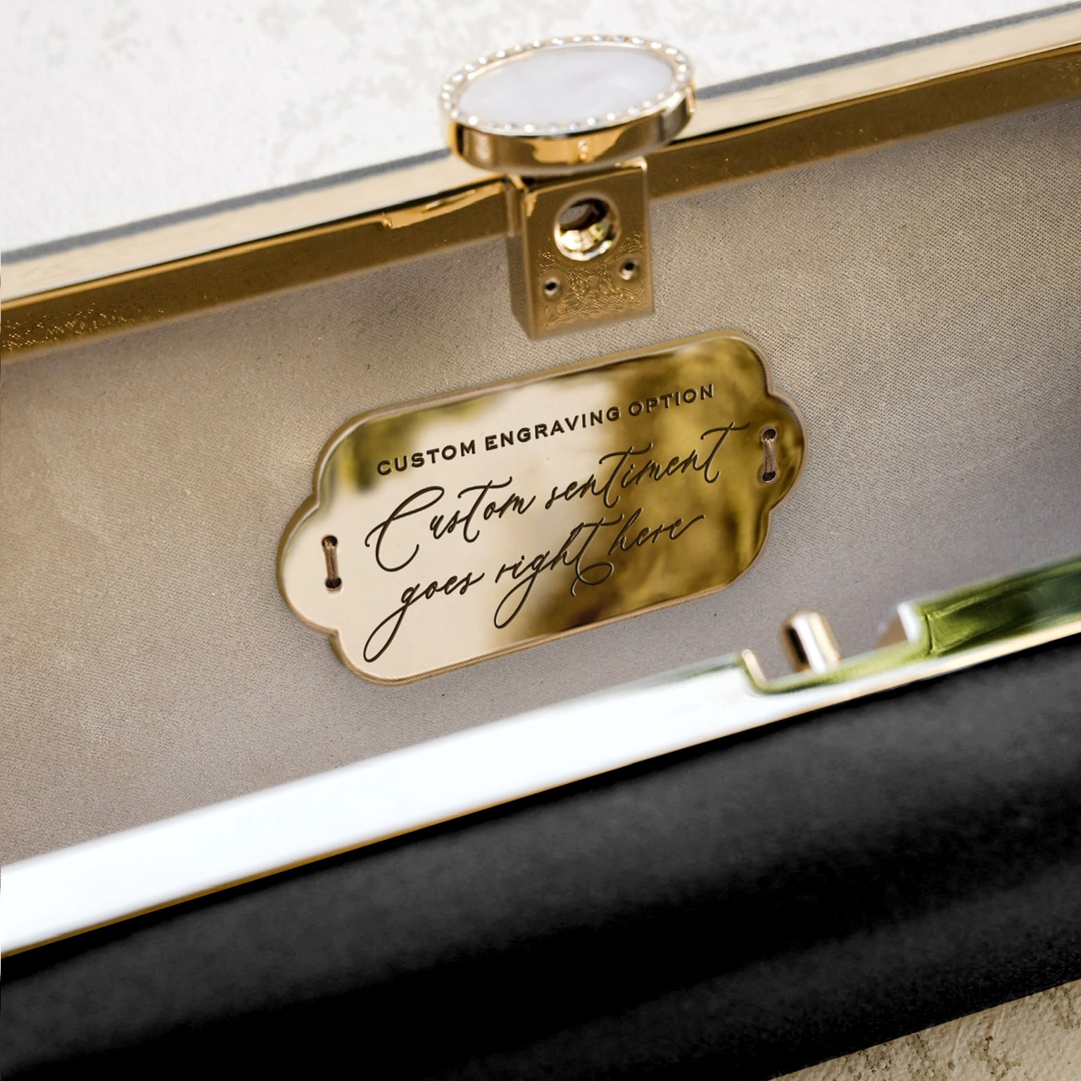 Gold plaque with custom engraving on a beige case interior of The Bella Rosa Collection's Bella Clutch Black Petite evening clutch.