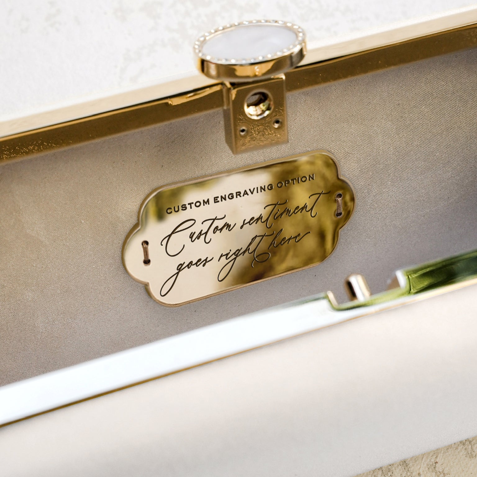 A close-up of a metal Bella Clutch Ivory Petite from The Bella Rosa Collection with a custom engraving option placeholder.