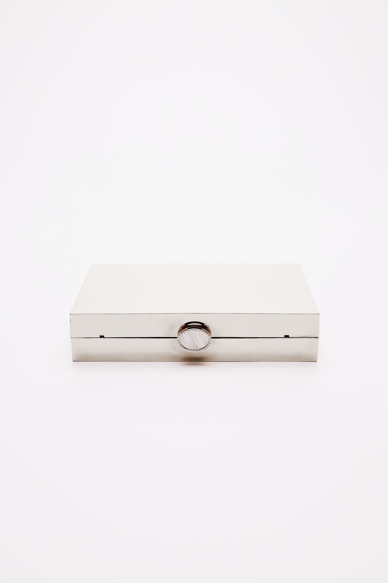 Talich clutch in reflective silver mirror laying on its side, showing the top clasp with a mother of pearl and crystal lined clasp.