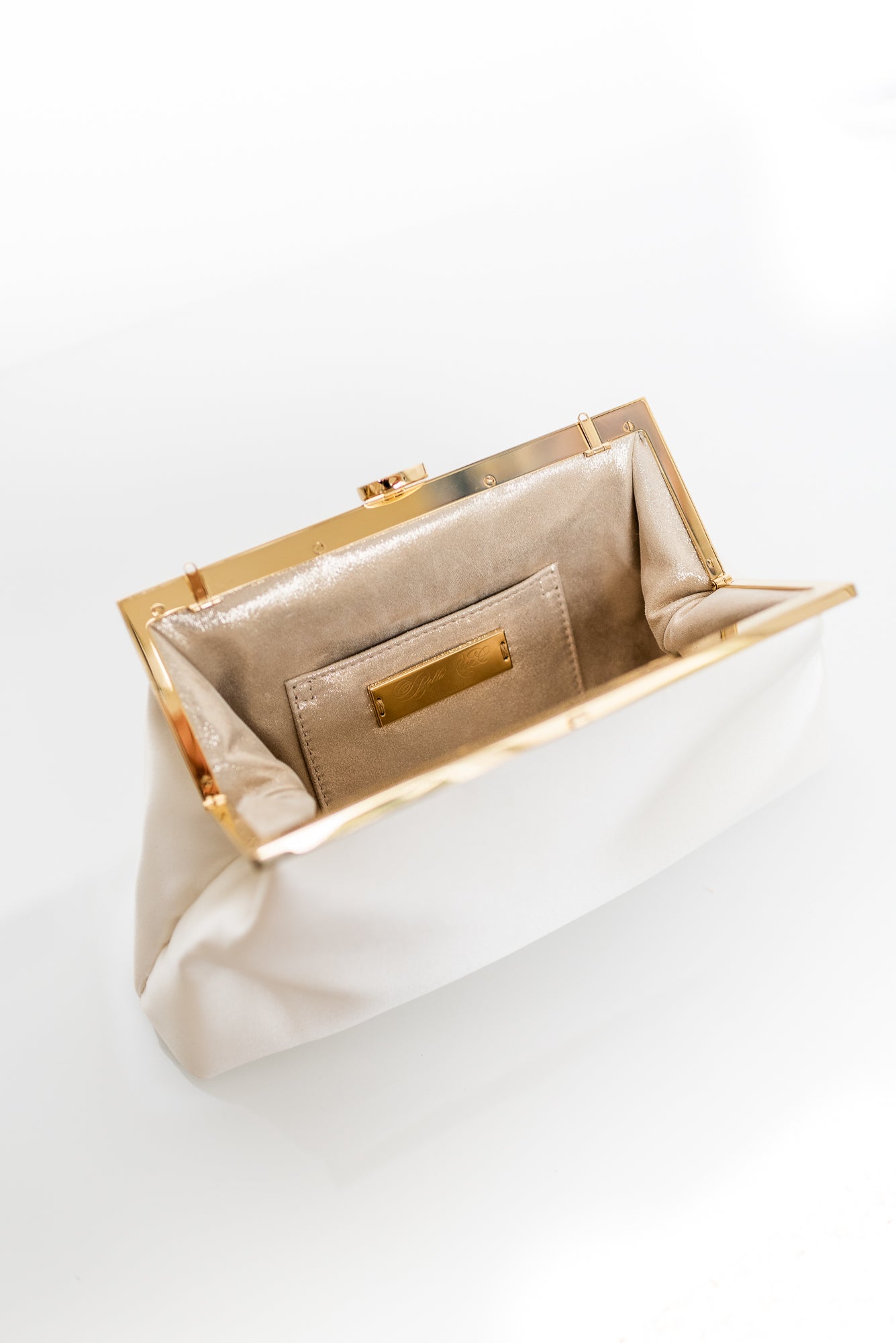 Open view of Rosa Clutch in Ivory white satin with gold hardware clasp frame.