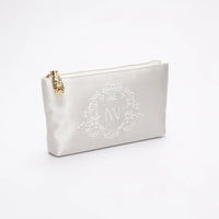 Side view of ivory satin zipper pouch with bridal crest monogram embroidery.