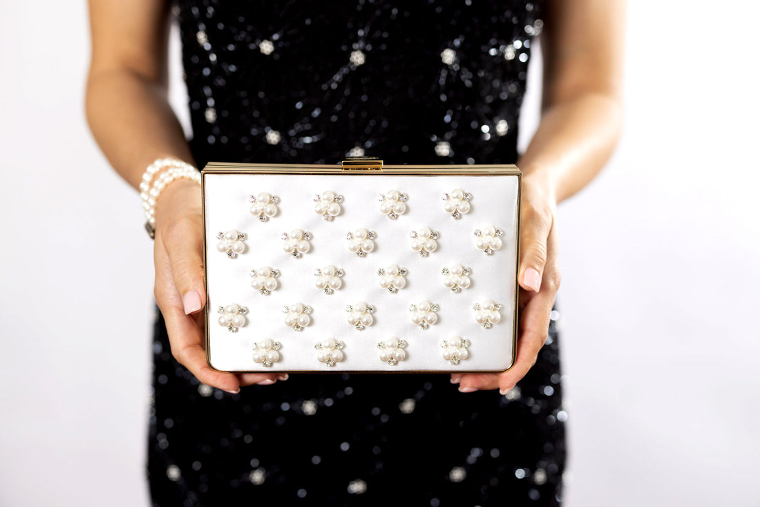 A woman holding a white Venezia Bridal Pearl with Crystals Clutch x MICAELA from The Bella Rosa Collection.