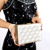 A woman in a black dress holding a Venezia Bridal Pearl with Crystals Clutch x MICAELA by The Bella Rosa Collection.