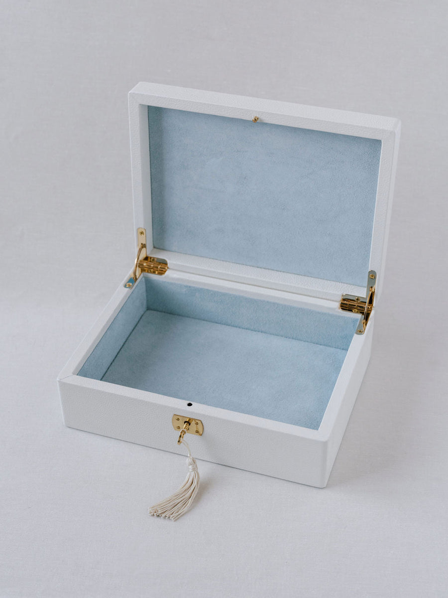 White Italian leather wedding day keepsake box with blue suede interior and gold lock and key accents. Wedding box is shown with top open and the key and tassel inserted into the lock.