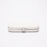 Bella Clutch in a shimmer white glitter body with a silver frame laying on side showing top clasp angle.