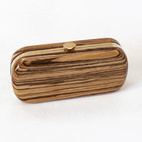 Side angle of Bella Clutch with a gold hardware frame in a solid African Zebra Wood Body.