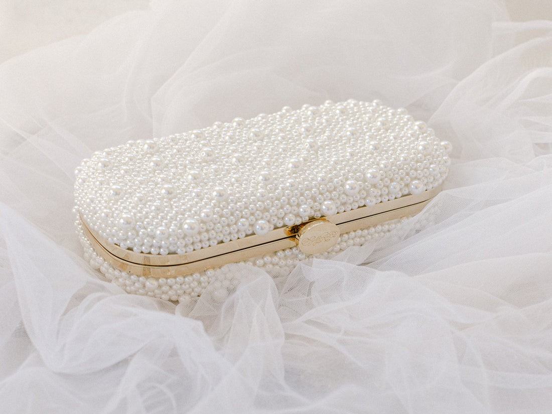 A True Love Pearl Pearl Clutch by The Bella Rosa Collection sitting on top of a white veil.