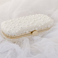 A True Love Pearl Pearl Clutch by The Bella Rosa Collection sitting on top of a white veil.