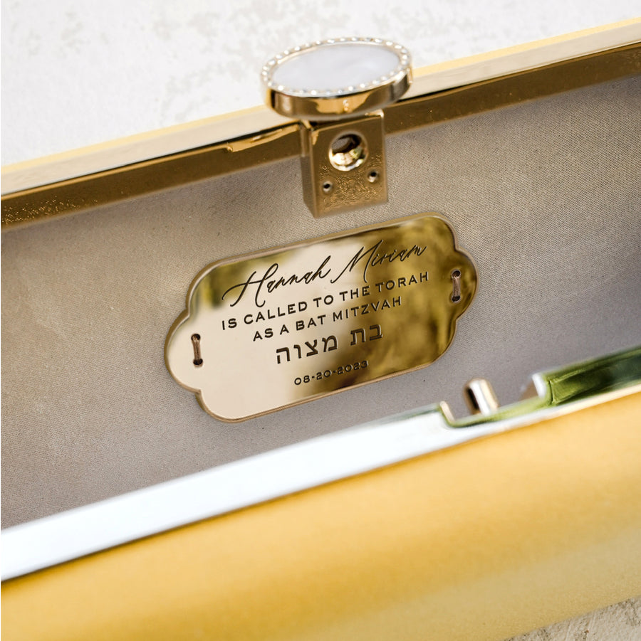 A Bat Mitzvah Personalized Bella Clutch Petite from The Bella Rosa Collection with a personalized name tag on it.