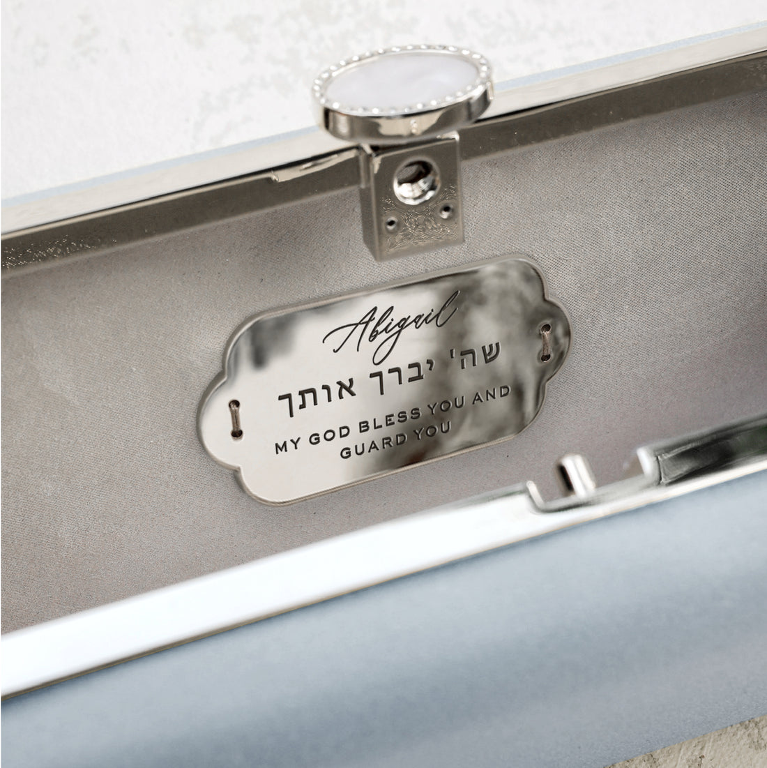 A personalized gift for a Bat Mitzvah, the Bat Mitzvah Personalized Bella Clutch Petite from The Bella Rosa Collection is a blue box with a Hebrew name on it.