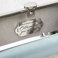 A personalized gift for a Bat Mitzvah, the Bat Mitzvah Personalized Bella Clutch Petite from The Bella Rosa Collection, features a blue box with a silver plaque on it.