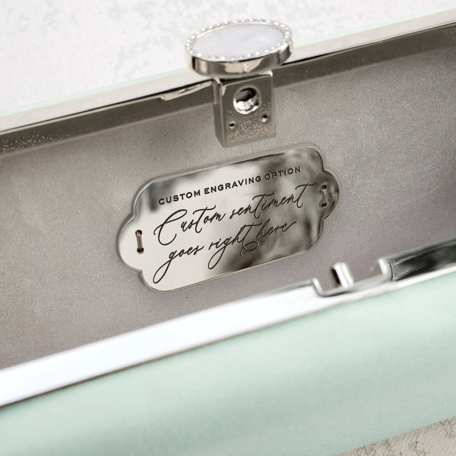 A Sage Green Satin Bella Clutch from The Bella Rosa Collection with a silver plate on it.