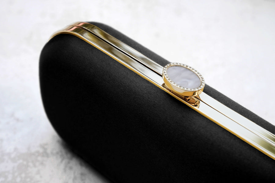 Close up view of Black Satin Bella Clutch with gold hardware and stimulated pearl clasp.