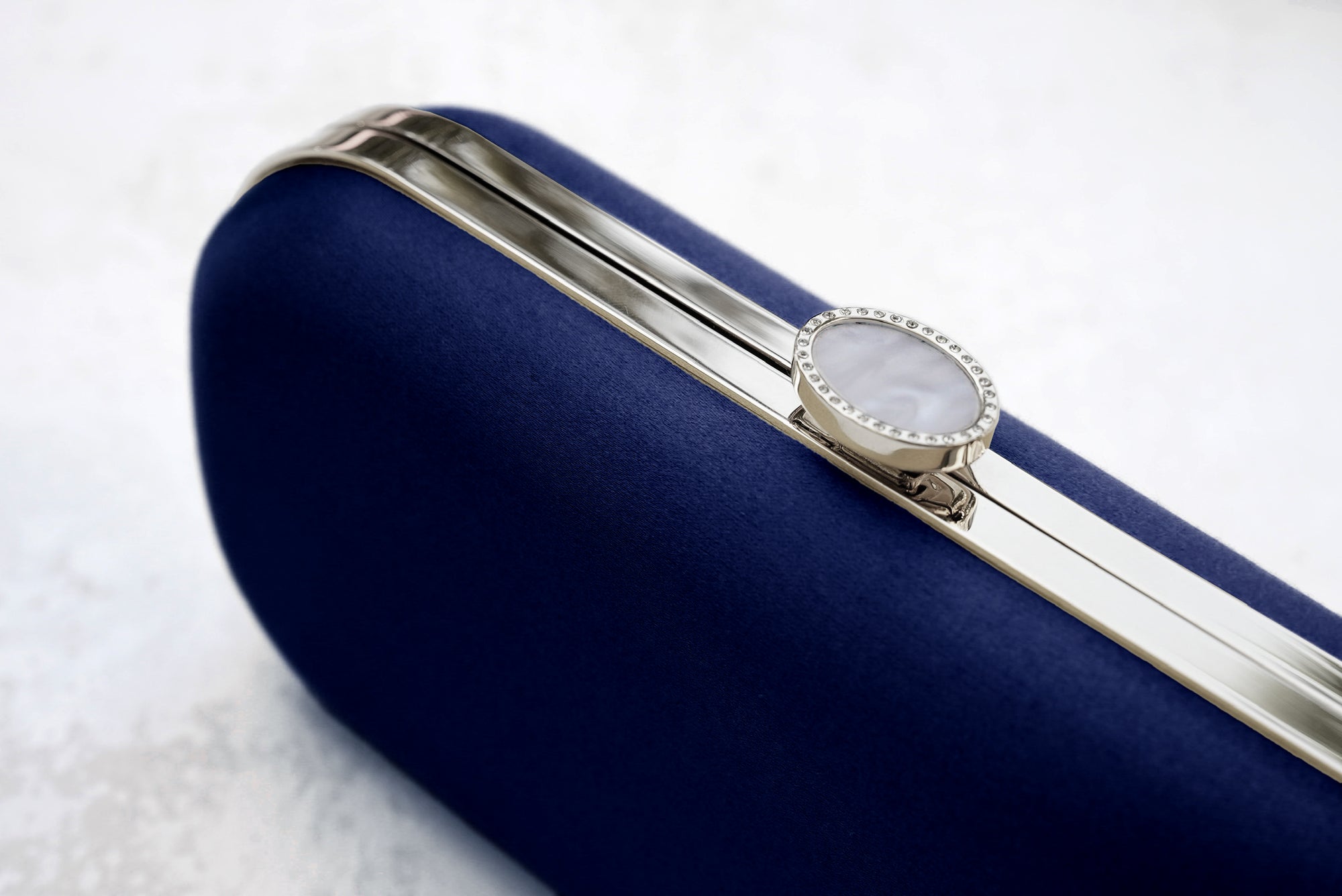 Elegant silver ring displayed on a Bella Clutch Navy Blue Petite from The Bella Rosa Collection.