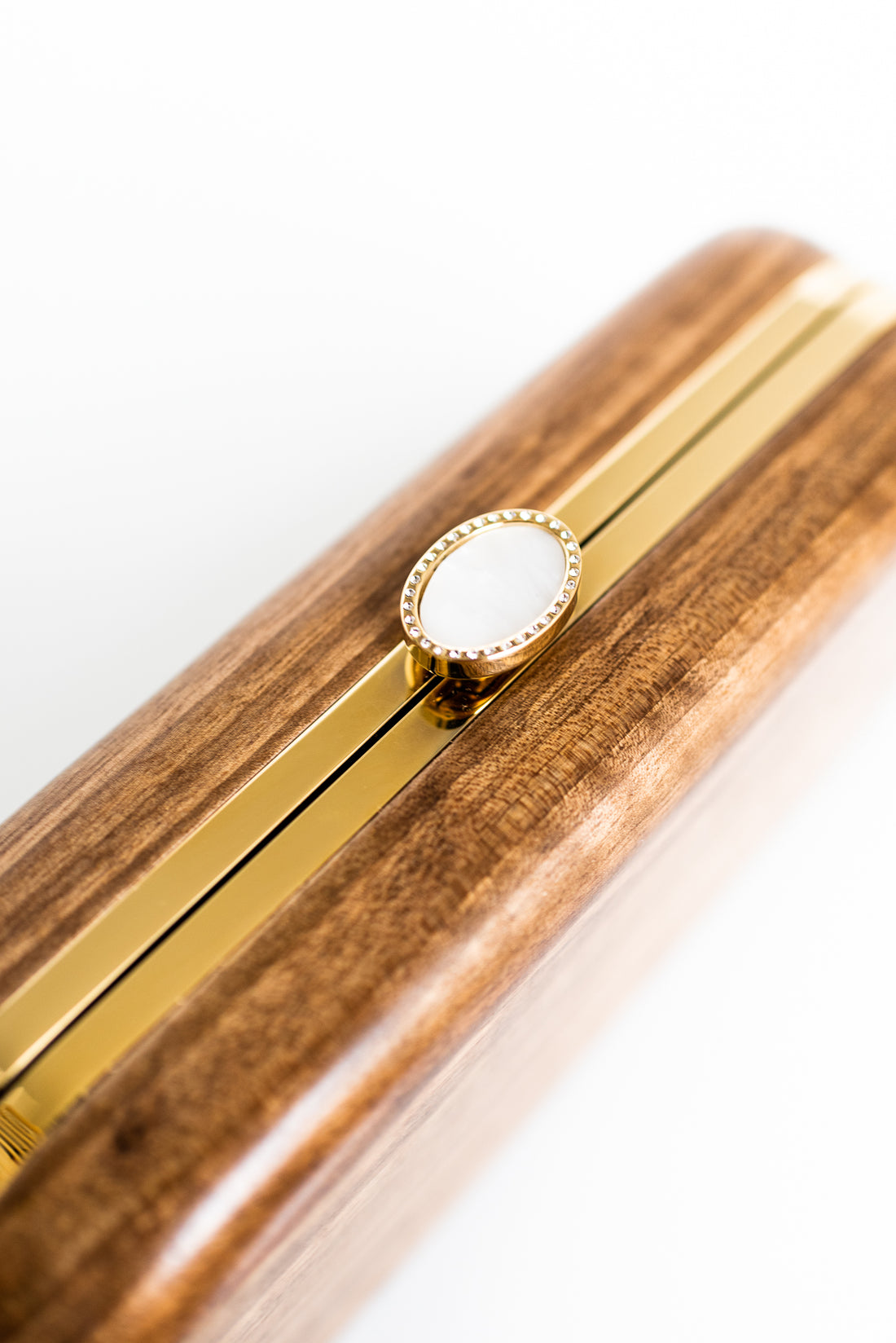 Bella Clutch with gold hardware frame in a solid Walnut Wood body and a stimulated mother of pearl clasp.