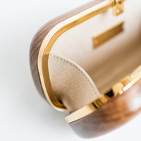 Bella Clutch with gold hardware frame in a solid Walnut Wood body.