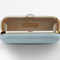 Top view of open bridal Bella Clutch in light iced blue with gold hardware accents and stimulated mother of pearl clasp. Open purse shoes tag detail of bag.