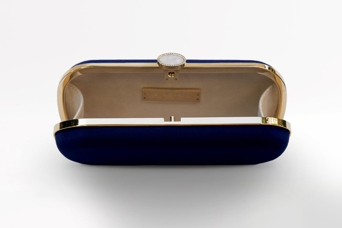The Bat Mitzvah Personalized Bella Clutch Petite, part of The Bella Rosa Collection, stands out with its elegant blue and gold design. Placed on a pristine white surface, this clutch bag is the perfect personalized gift for Bat Mitzvah celebrations.