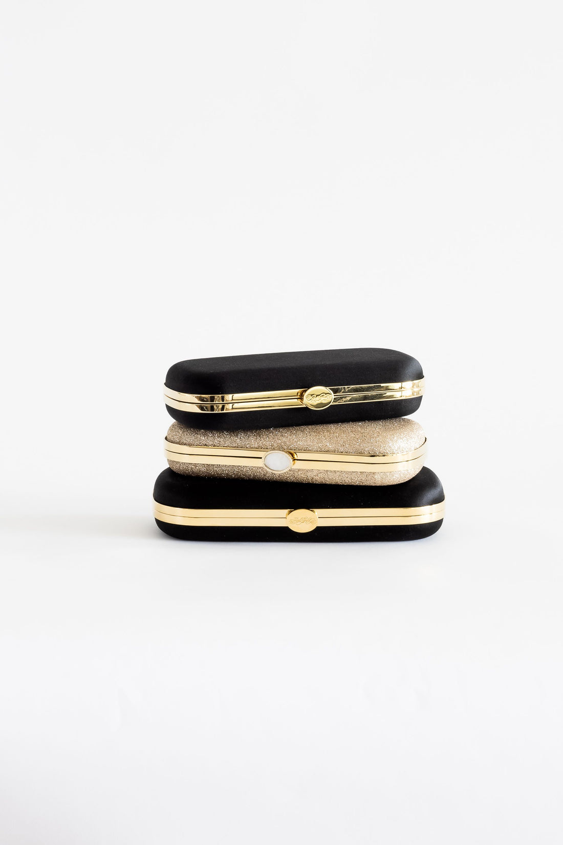 Three Black Satin Bella Clutches from The Bella Rosa Collection stacked on top of each other.