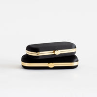 two Black Satin Bella Clutches from The Bella Rosa Collection on a white surface.
