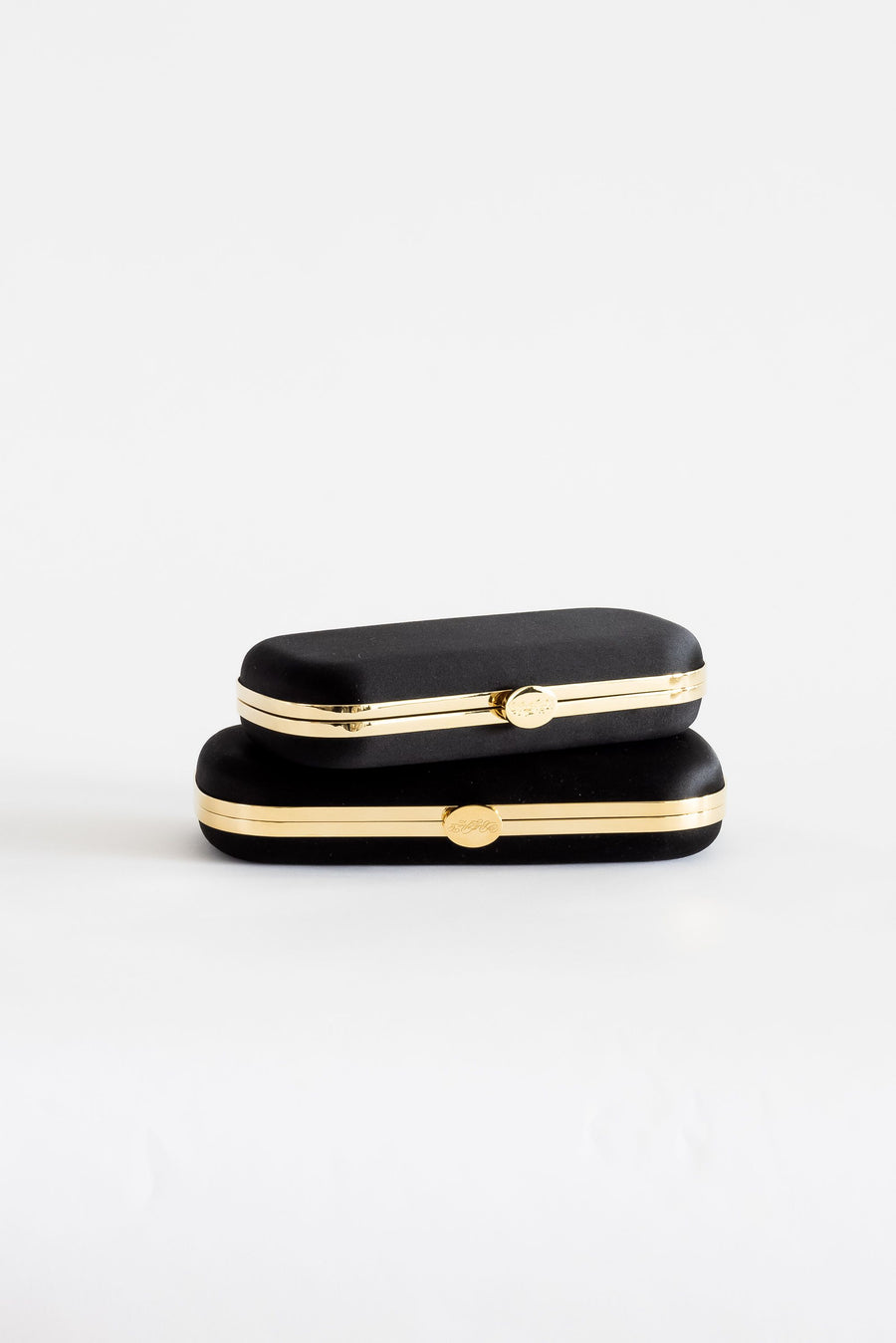two Black Satin Bella Clutches from The Bella Rosa Collection on a white surface.