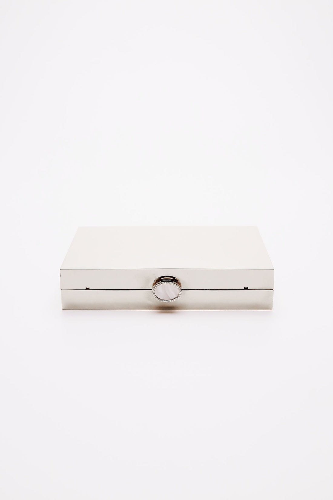 Talich clutch in reflective silver mirror laying on its side, showing the top clasp with a mother of pearl and crystal lined clasp.