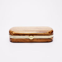 A sustainably sourced Bella Clutch African Zebra Wood Petite eyeglass case with a metal clasp on a white background by The Bella Rosa Collection.