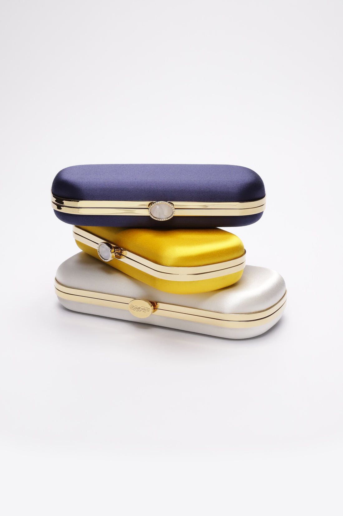 Three stacked Bella Clutches in Navy Blue, yellow and ivory