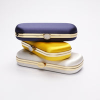 Three stacked Bella Clutches in Navy Blue, yellow and ivory
