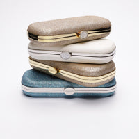 Four shimmer glitter Bella Clutches stacked on top of each other.