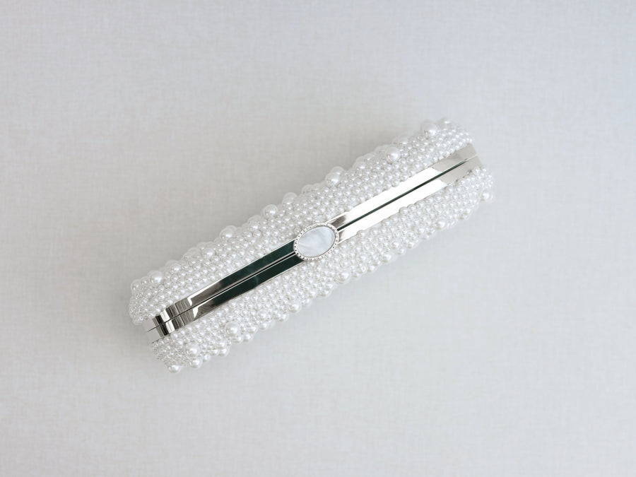 A close up of Over the Moon's True Love Bella Pearl Clutch on a white surface.