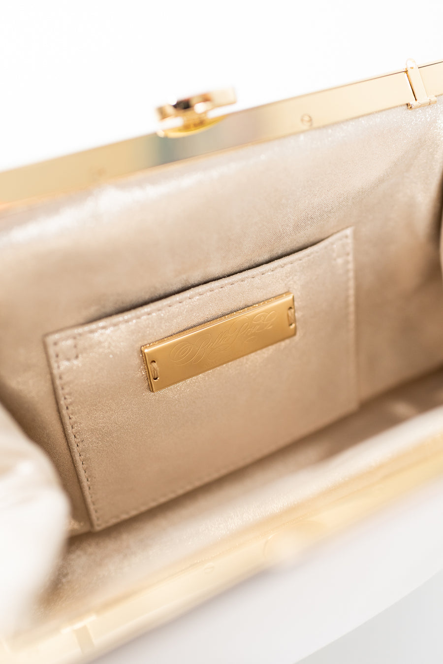Close up open view of Rosa Clutch in Ivory white satin with gold hardware clasp frame.