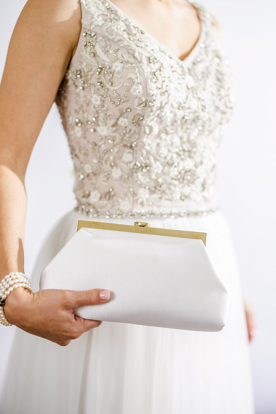Bride holding ivory white Rosa Clutch with gold clasp haardware.