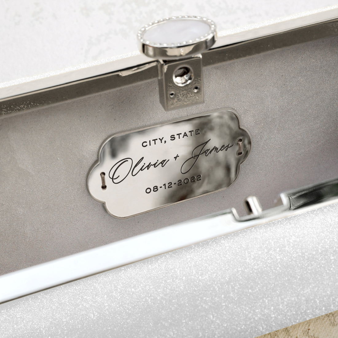 a Snow White Shimmer Bella Clutch from The Bella Rosa Collection with a name plate on it.